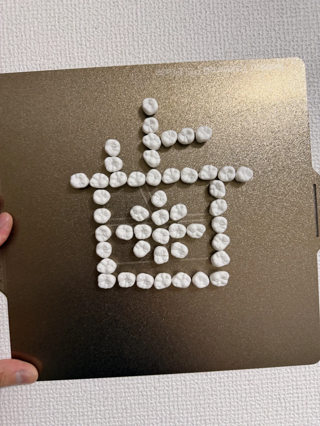 金属の板に歯グネットを付けて、歯の文字の形に並べた様子