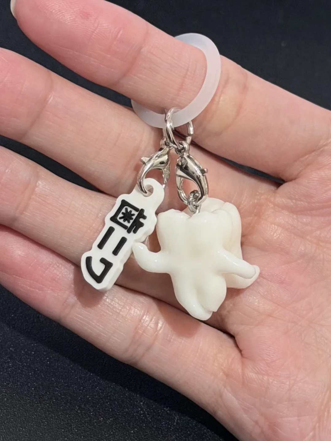 手のひらに載せた歯ニワとネームタグ付きのめじるしアクセサリー