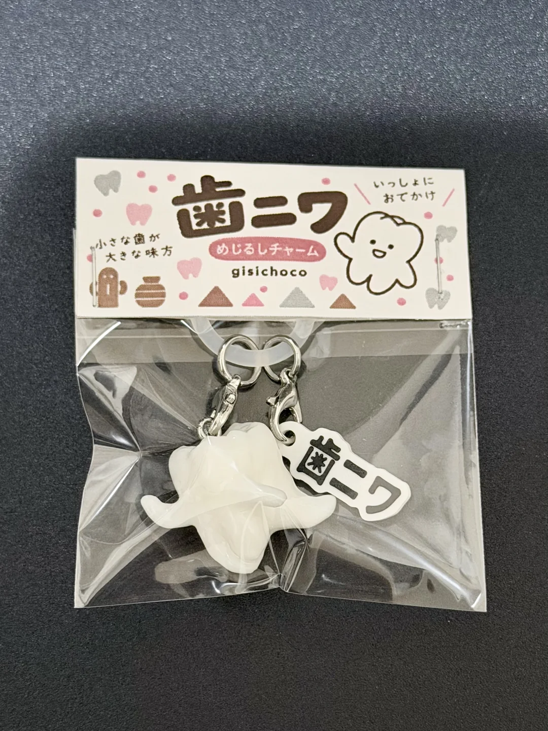 歯ニワのイラスト入り台紙とともに袋に入った、歯ニワのめじるしアクセサリー
