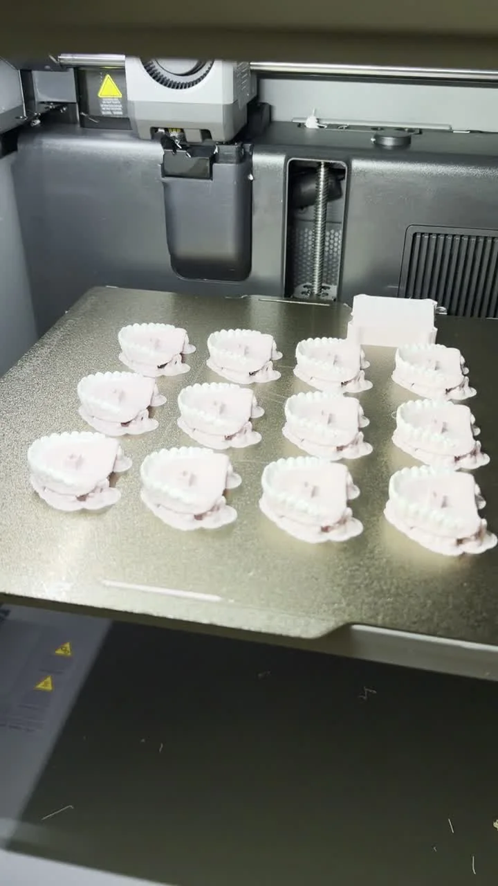 3Dプリンターに並ぶ入れ歯クリッカーキーホルダーの白いパーツ
